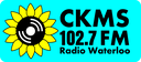 Sunflower with a vinyl record centre logo and CKMS 102.7 FM Radio Waterloo wordmark on a light blue field